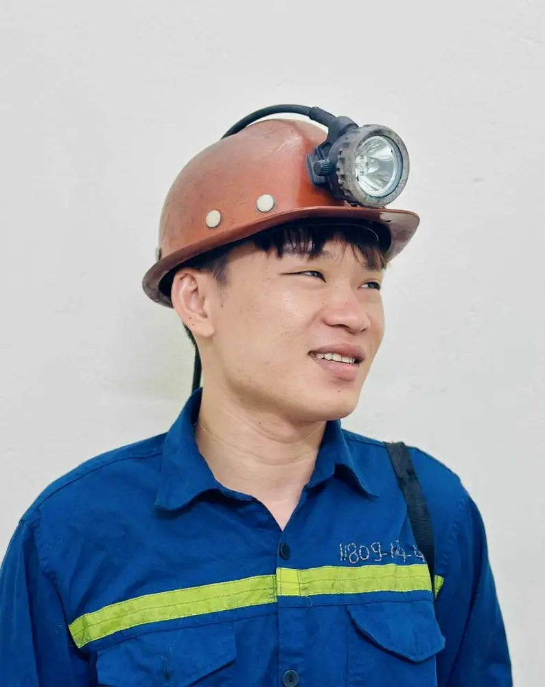 Công nhân trẻ Lò Văn Kỷ mặc bảo hộ xanh, đội mũ và đèn lò