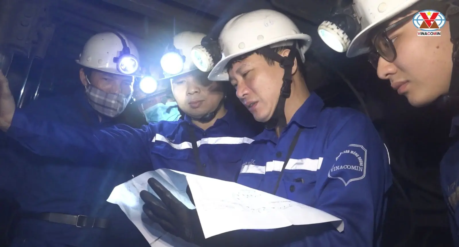 Nhóm công nhân Than Mông Dương mặc bảo hộ xanh, đội mũ trao đổi bản vẽ